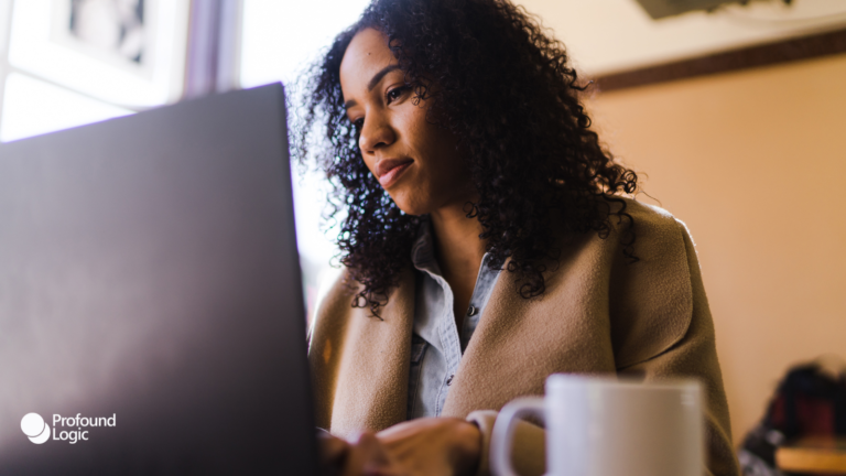 A women in a blazer sitting at a table with their laptop