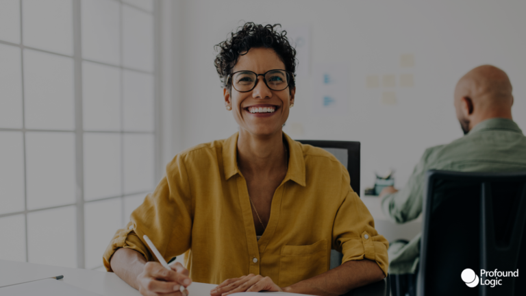 A smiling person working at their desk in an office