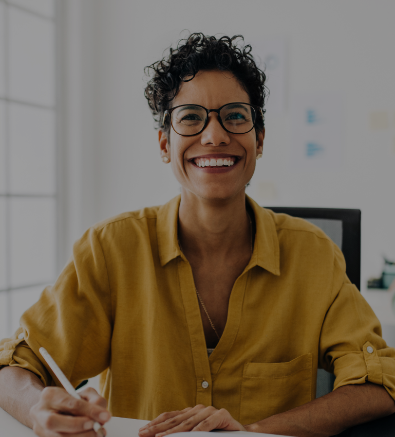 A smiling person working at their desk in an office