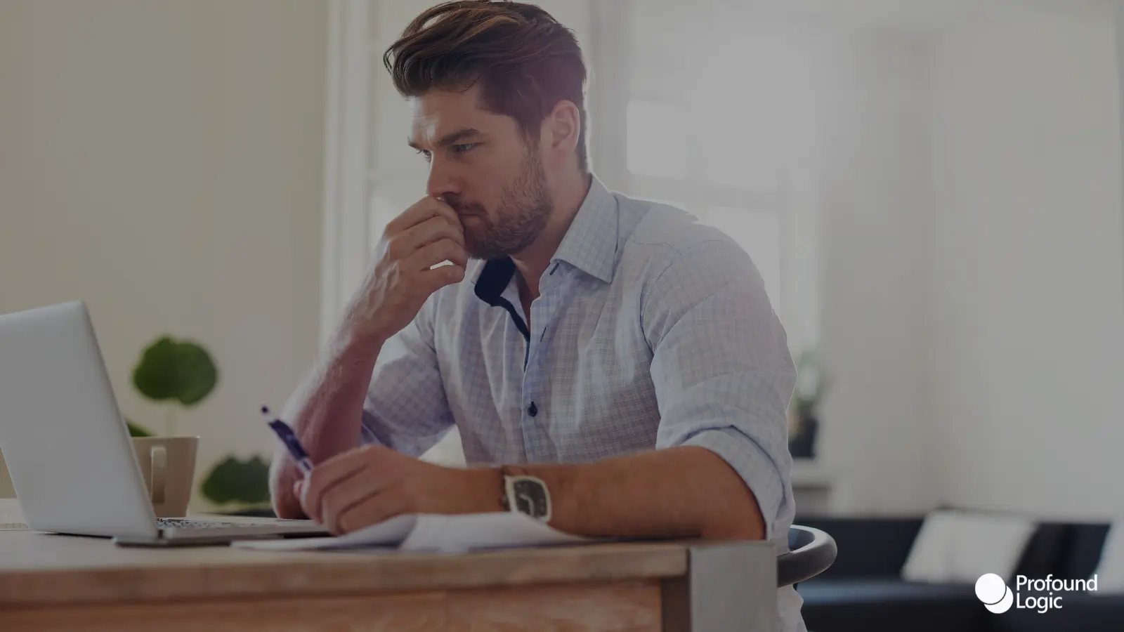 a person sitting at a table with a laptop and pen