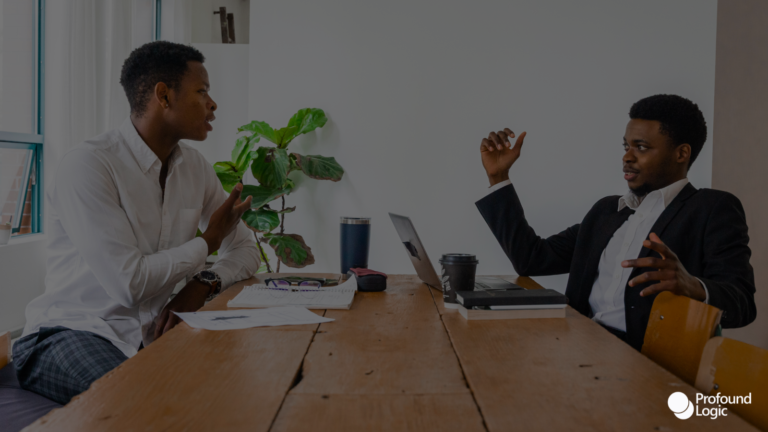 two individuals sitting at a table in an office