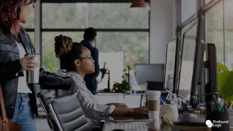 Two people working on computers in an office setting.