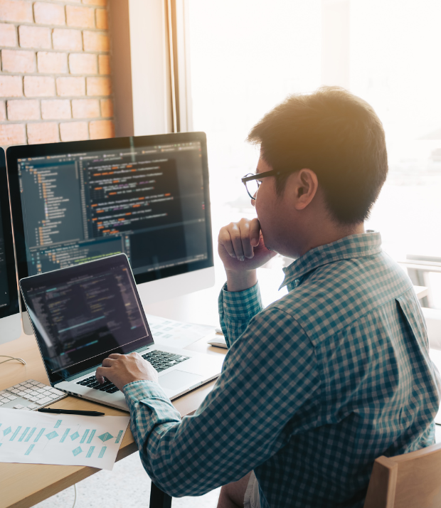 person looking at two monitors with code on